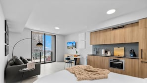 A modern apartment with a large window, a dining area, a kitchenette, and a living space with a sofa and a laptop. - 501 First Studio with Luxury Amenities (Miami)