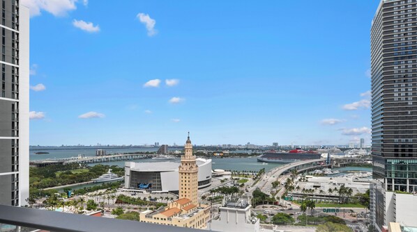 A cityscape with a prominent tower, a large cruise ship docked, and a bridge spanning a body of water. - 501 First Studio with Luxury Amenities (Miami)