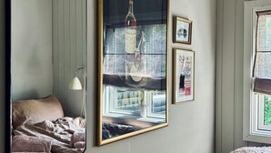 Un dormitorio con una cama, un espejo grande y cuadros en la pared.