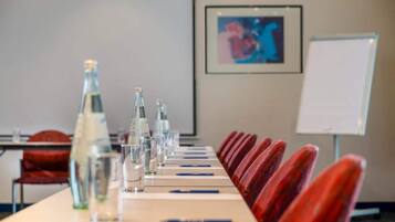 Een vergaderruimte met een lange tafel, stoelen, waterflesjes, glazen en een whiteboard.