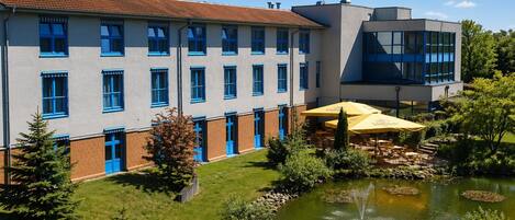 A building with a courtyard, a pond, and outdoor seating.
