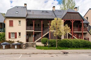 Ein zweigeschossiges Gebäude mit Balkon, Treppe und einer kleinen Veranda.