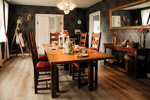 Una sala da pranzo con tavolo in legno, sedie, un lampadario e uno specchio.
