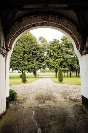 An arched brick structure with a gravel path leading to a grassy area.