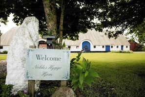 A welcome sign at the entrance of a building with a blue door and a white facade.