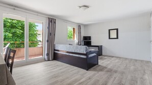 Une chambre à coucher avec un lit, une télévision et un balcon avec des rideaux.