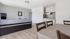 Une chambre avec un lit, une table à manger avec des chaises, un coin cuisine et un téléviseur.