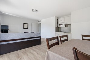 A bedroom with a bed, a dining table with chairs, a kitchenette, and a television. - Functional Holiday Base in Grasse (Grasse)