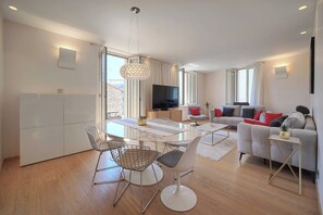 Un salon moderne comprenant un coin repas, un ensemble de canapés et un téléviseur.