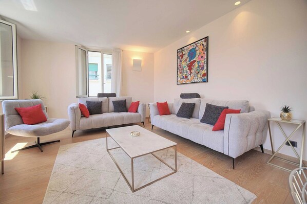 A modern living room with two grey sofas, a white coffee table, and a colorful abstract painting on the wall. - Stunning Apartment a/c 6P with Sea View - Cannes (Cannes)