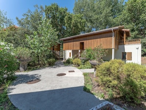 A modern building with a wooden exterior, a covered outdoor area, and a paved pathway leading to the entrance. - 4-guest Stay Near Moutchic Beach (Lacanau)