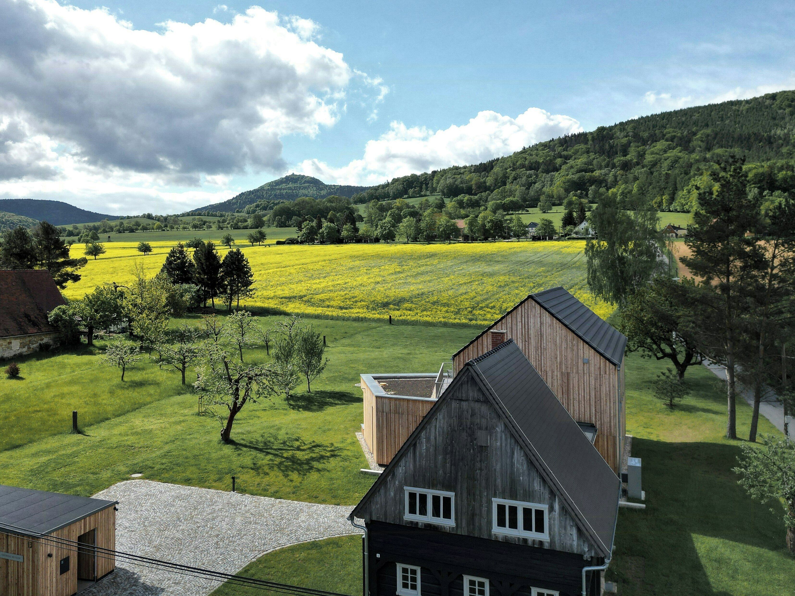 Een landelijk landschap met een schuur, open velden en een heuvel op de achtergrond.