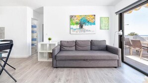A modern living room with a grey sofa, a painting, and a 'ENJOY THE LITTLE THINGS' sign. - Palm Beach Suite - Playa del Cura (Mogán)