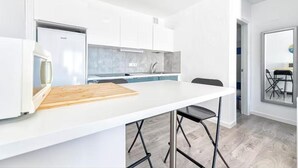 A modern kitchen with white cabinets, a white countertop, and a wooden cutting board. - Palm Beach Suite - Playa del Cura (Mogán)