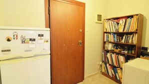 Eine Küche mit Kühlschrank und Holztür, ein Bücherregal mit Büchern sowie ein weißes Gerät.
