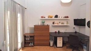 Ein Zimmer mit einem Holztisch, einem Computer, einem Stuhl, einer Heizung, einem Regal mit Spielzeug und einem Globus.