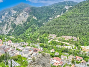 A mountainous town with residential buildings, a clear sky, and dense forested hills. - Lovely Apartment for 7-guests (Guillaumes)