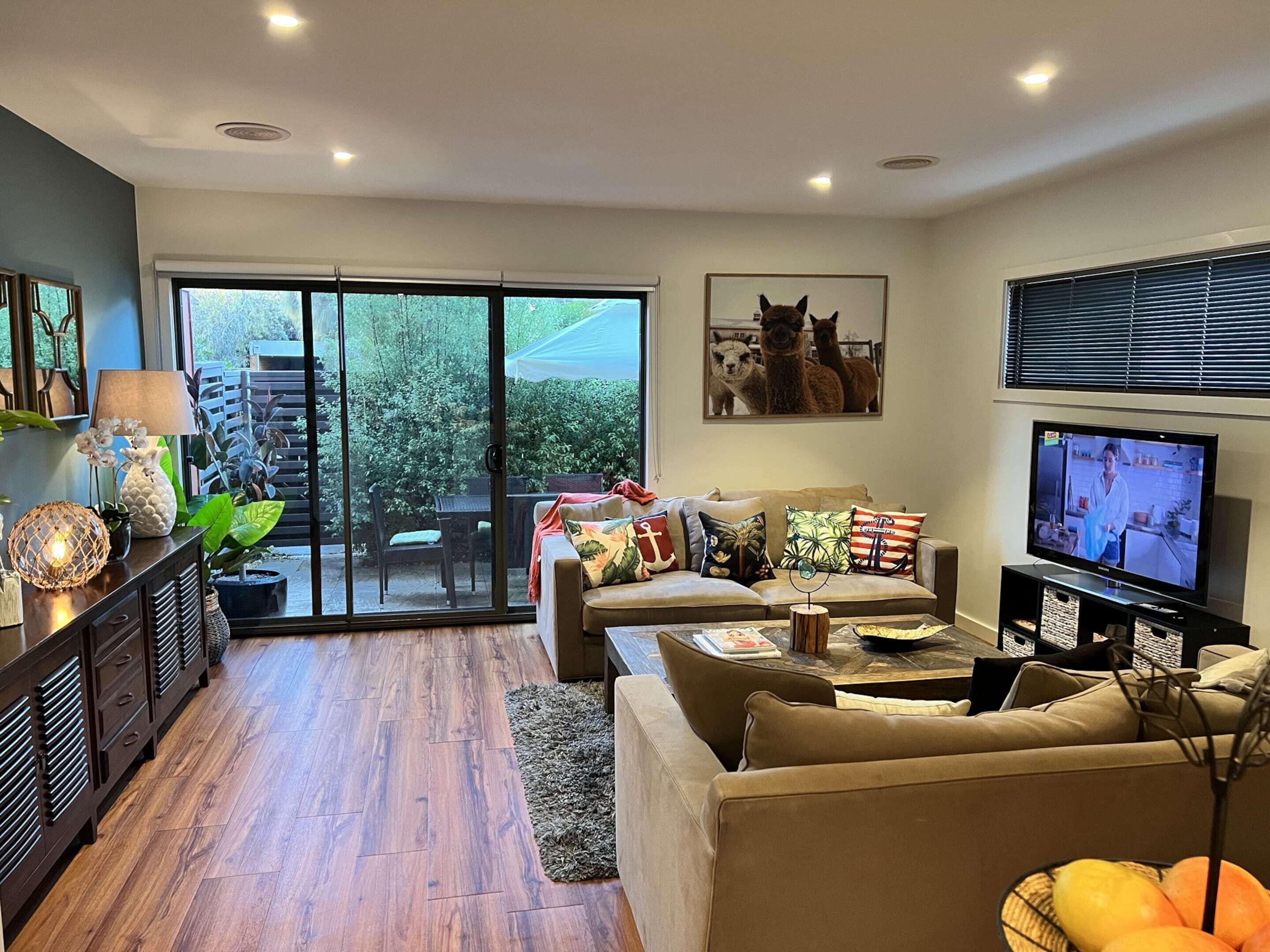A living room with a sofa, TV, and a sliding glass door leading to an outdoor area.