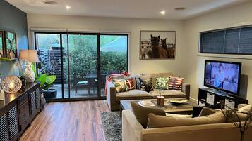 A living room with a sofa, TV, and a sliding glass door leading to an outdoor area.