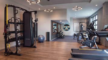 Une salle de sport équipée de matériel d’exercice, dotée d’un mur avec des miroirs et décorée d’œuvres d’art inspirantes.