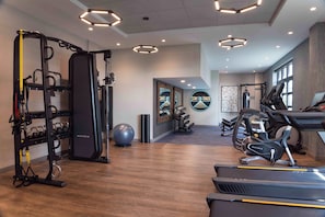 Une salle de sport équipée de matériel d’exercice, dotée d’un mur avec des miroirs et décorée d’œuvres d’art inspirantes.