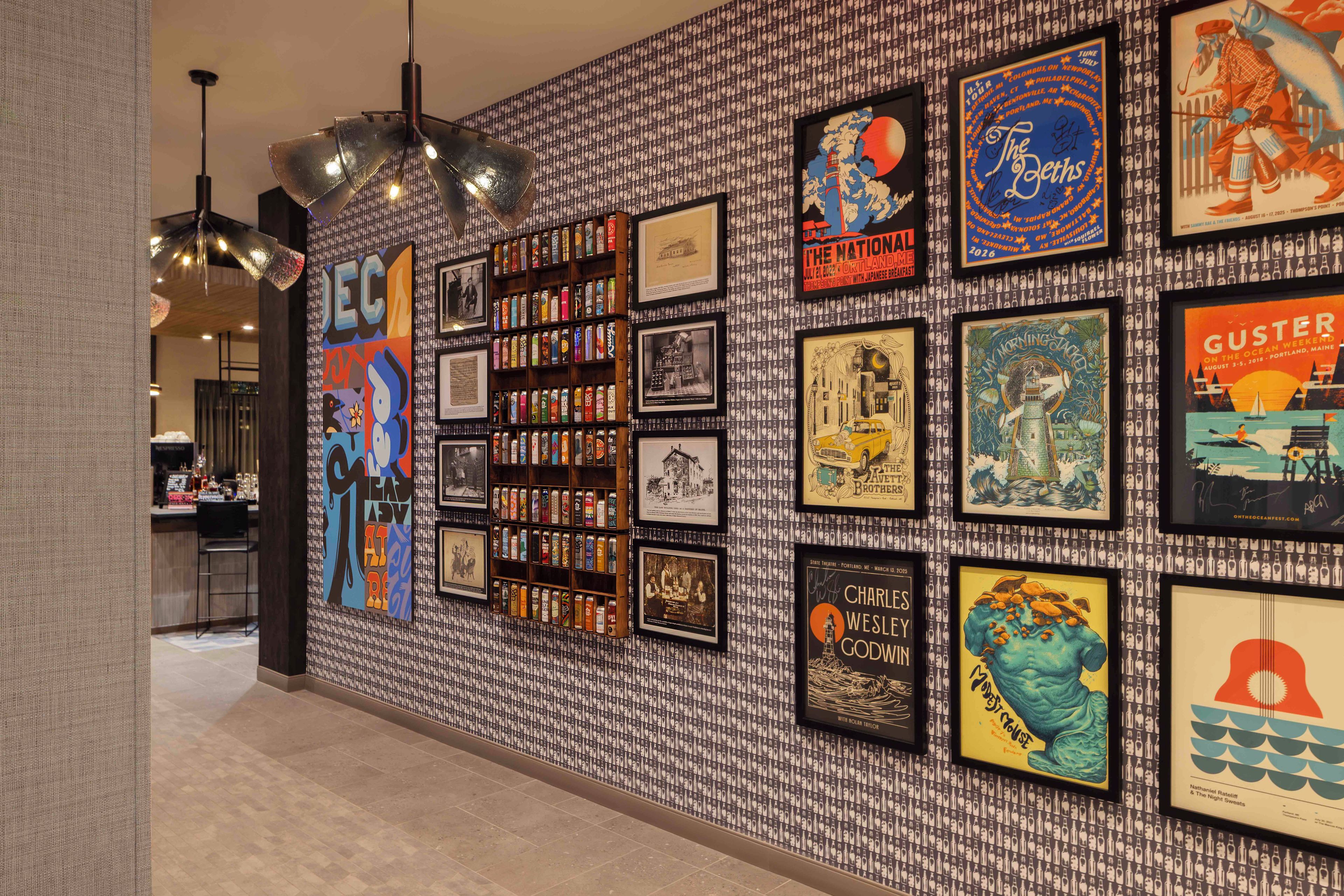 A wall with framed posters and a shelf of cans.