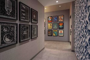 A hallway with framed artwork on the walls and a patterned wallpaper on the right.