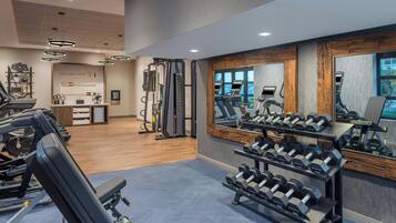 A gym with treadmills, weight benches, and dumbbells.
