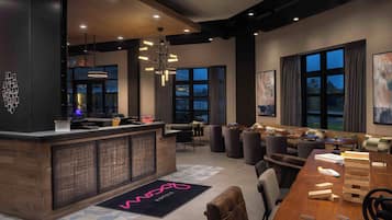 Een moderne hotellobby met een receptiebalie, zithoek en grote ramen.
