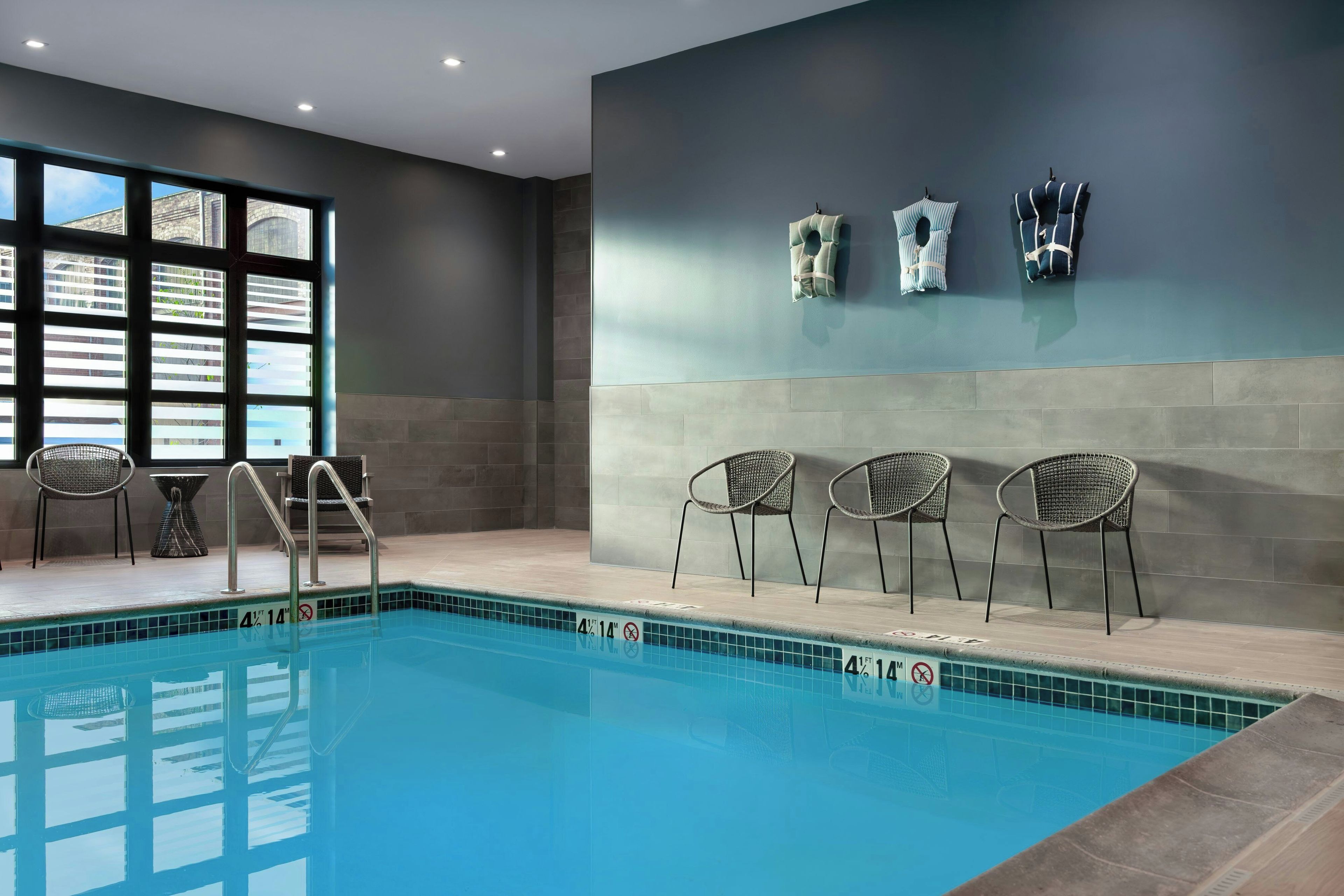 An indoor swimming pool with a clear view of the cityscape through large windows.