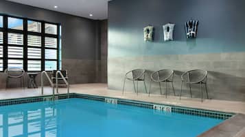 An indoor swimming pool with a clear view of the cityscape through large windows.