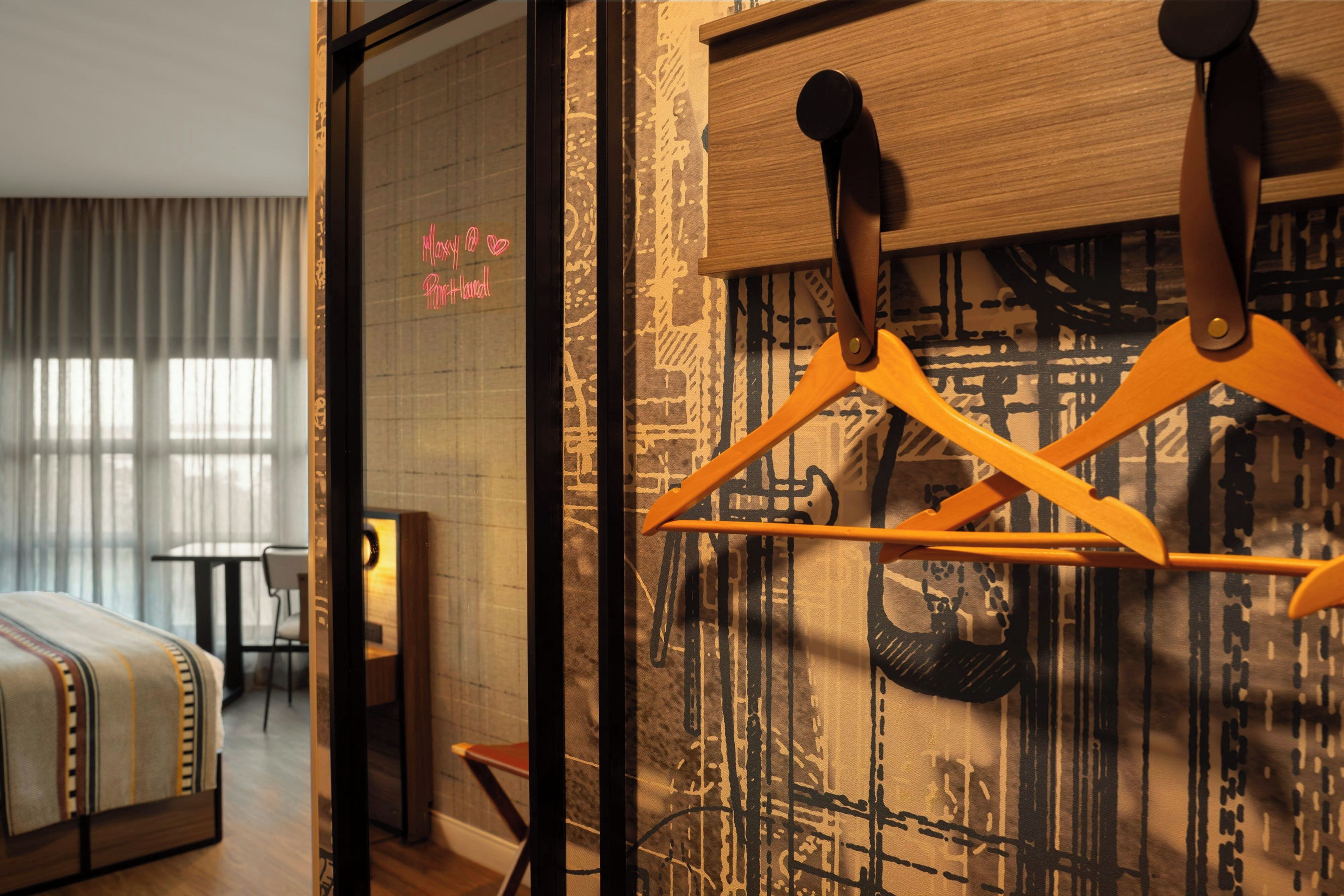 Une chambre d’hôtel avec un lit, une chaise et un porte-manteau avec des cintres.