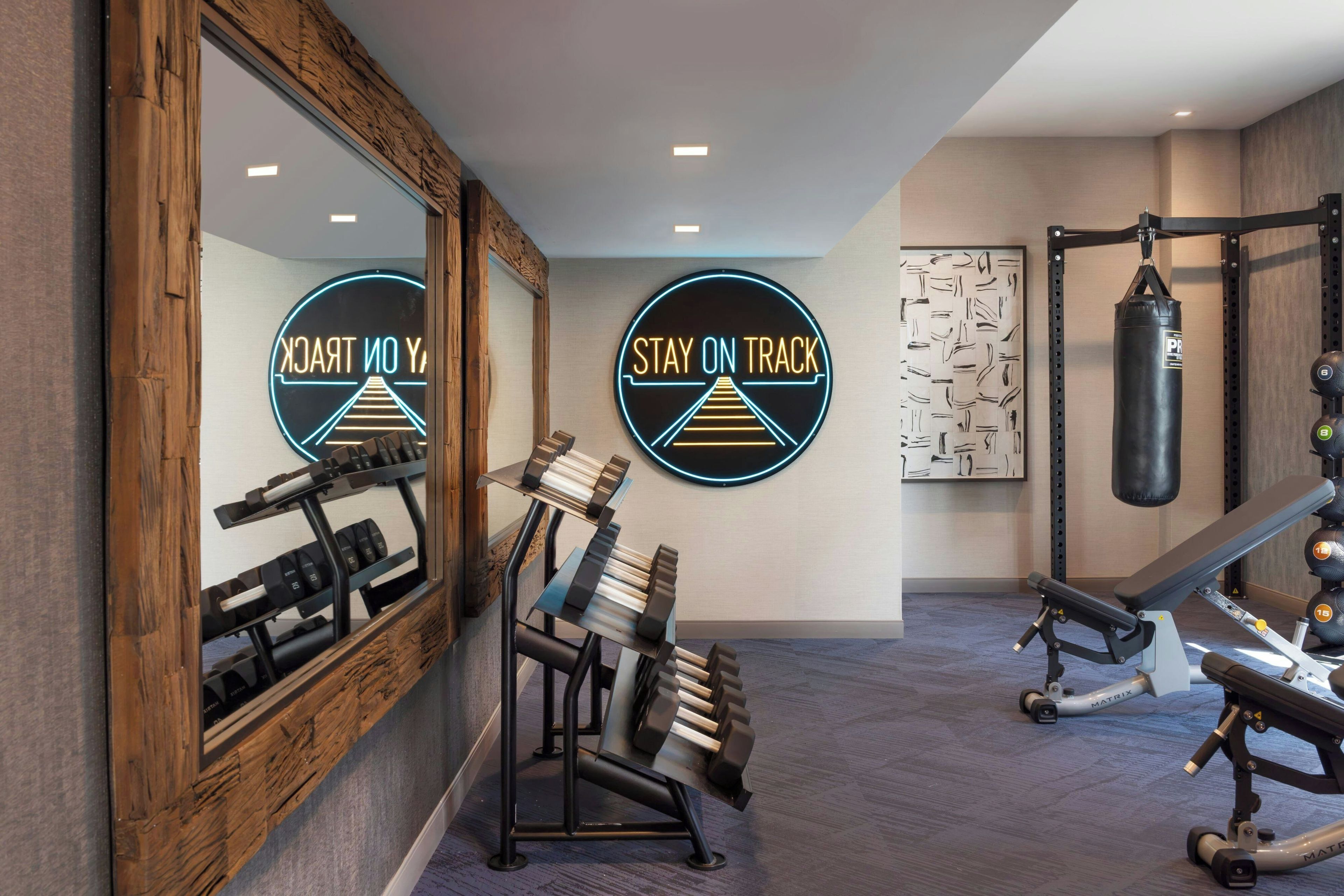 A gym with exercise equipment, a punching bag, and motivational wall art.