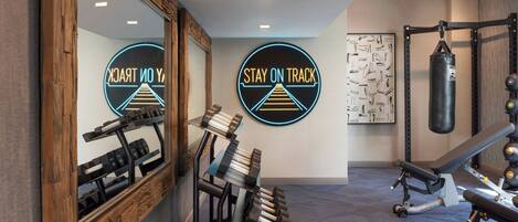 A gym with exercise equipment, a punching bag, and motivational wall art.