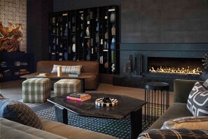 Un salon moderne avec une cheminée, un canapé, des poufs et une table basse.