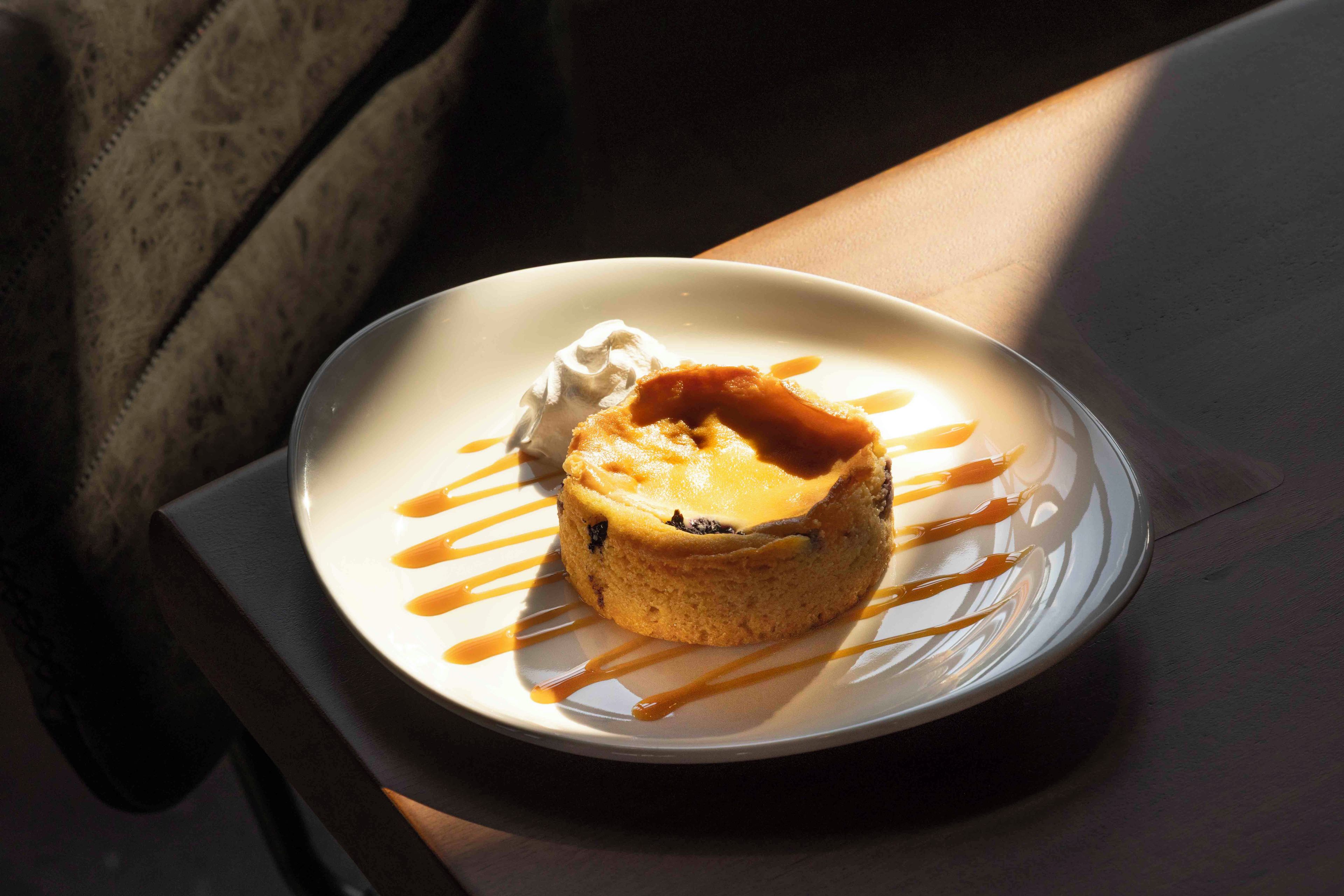 Un postre sobre un plato blanco con salsa de caramelo y una cucharada de crema.
