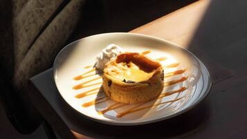Un postre sobre un plato blanco con salsa de caramelo y una cucharada de crema.