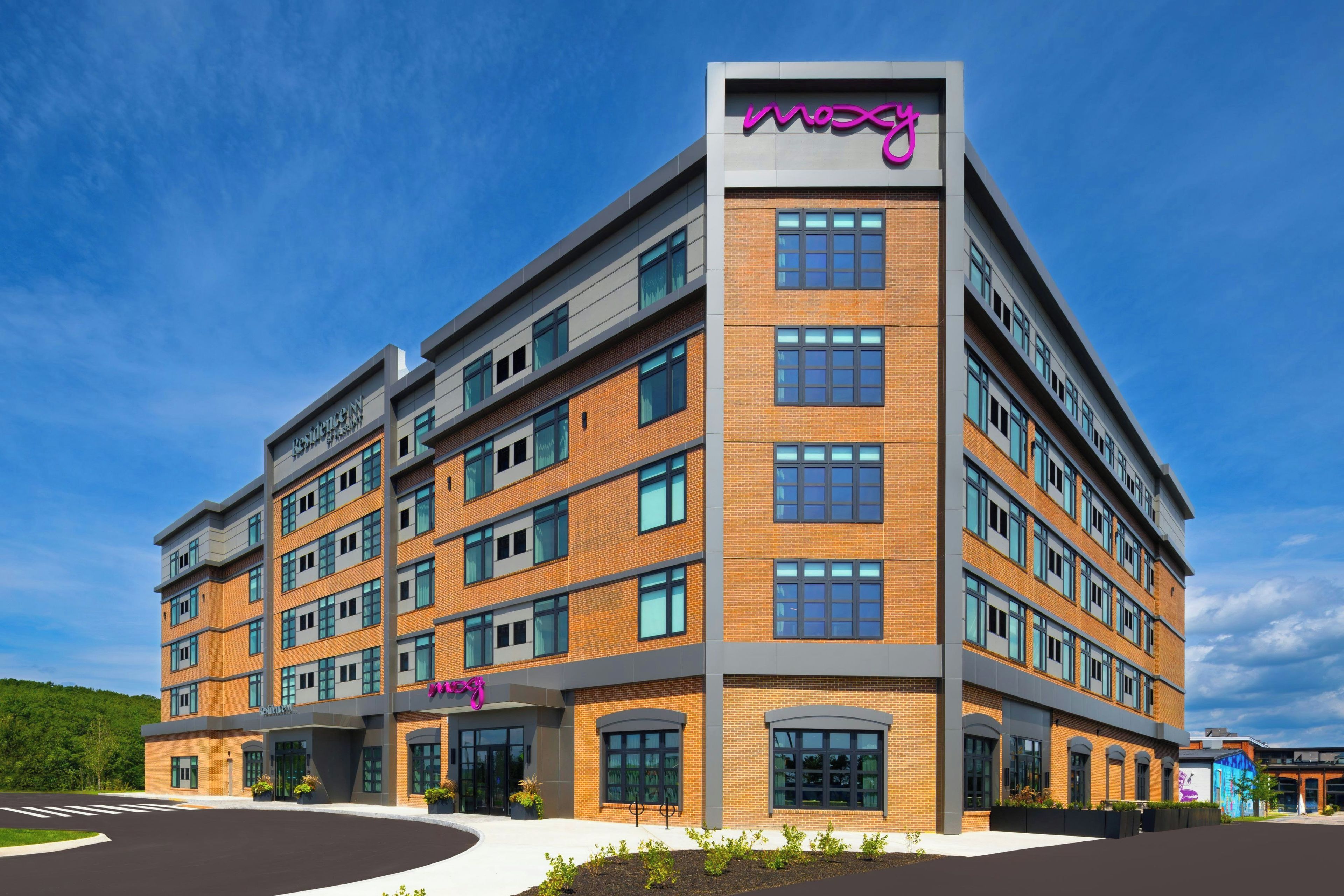 Een meerlaags gebouw met een opvallend 'mozy'-bord, uitgevoerd in een modern architectuur met baksteen- en glaselementen.