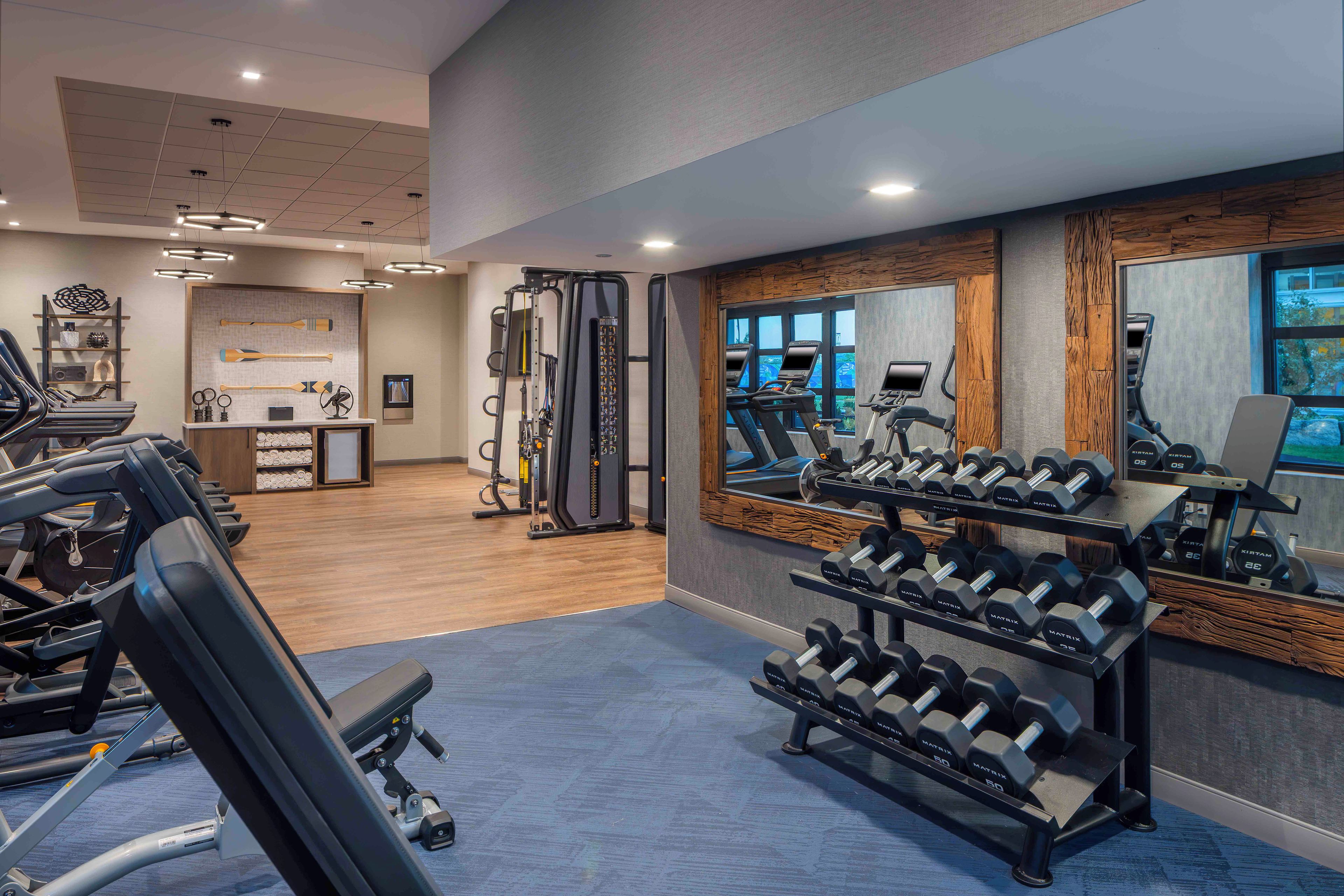 A gym with treadmills, weight machines, and a mirror reflecting the equipment.