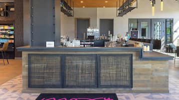 A hotel reception area with a bar, seating, and a staircase.