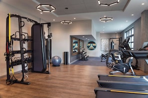 Un gimnasio con cintas de correr, máquinas de pesas y pelotas de ejercicio.