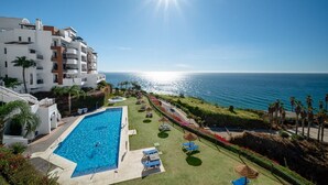 A hotel with a swimming pool, a view of the ocean, and a well-maintained lawn. - Apartment 'Ocean Vista Calaceite' with Sea View, Swimmingpool and South-facing terrace (Torrox Costa)