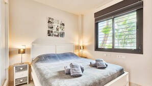 A bedroom with a bed, two bedside tables with lamps, a wall art piece, and a window with blinds. - Apartment 'Ocean Vista Calaceite' with Sea View, Swimmingpool and South-facing terrace (Torrox Costa)