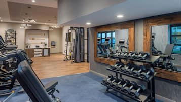 A gym with treadmills, weight machines, and a rack of dumbbells.
