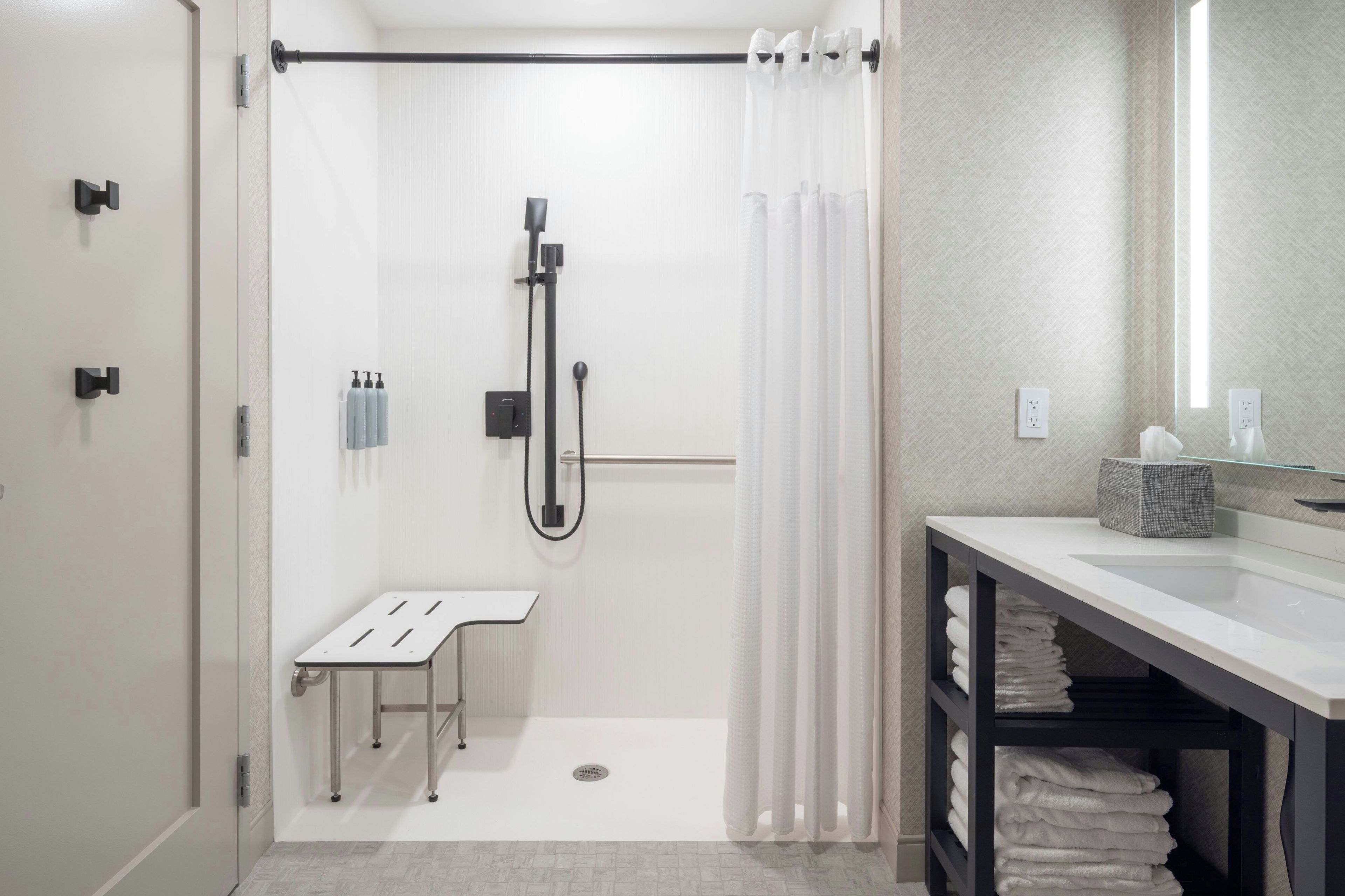 A modern bathroom with a shower, a sink, and a mirror.