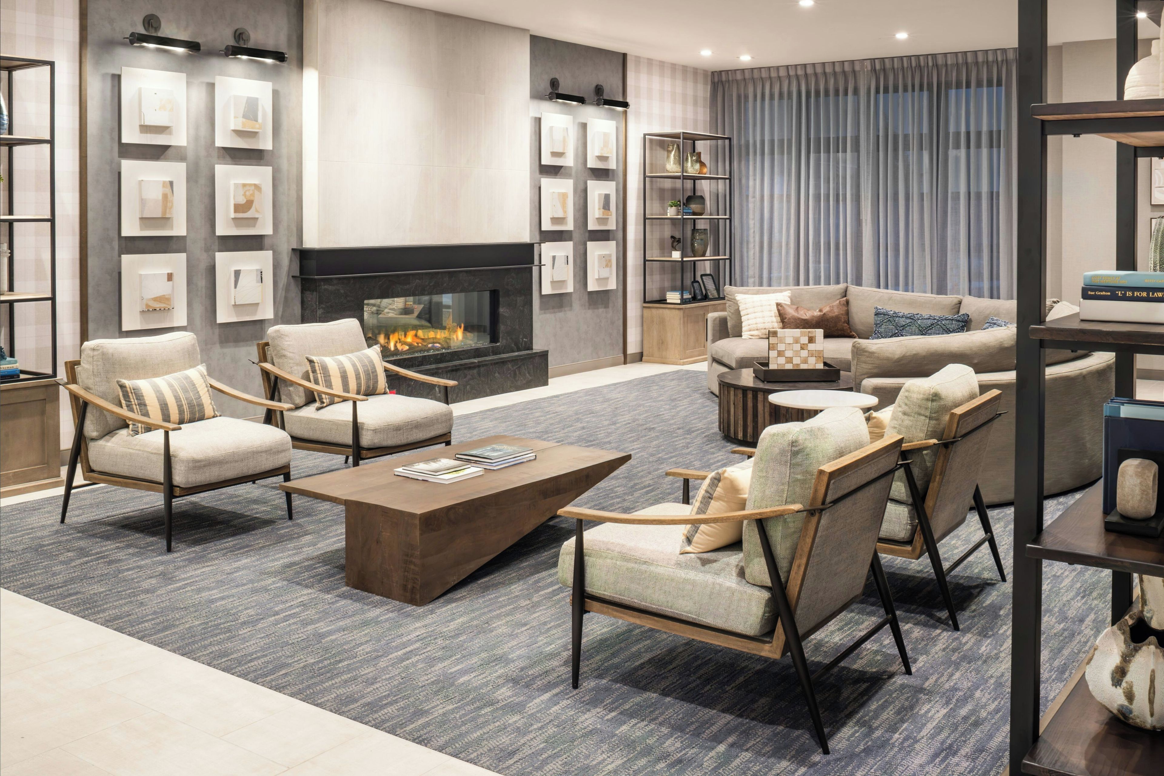 A modern living room with a fireplace, seating area, and bookshelves.
