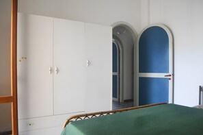Un dormitorio con cama, armario y puerta que da a otra habitación.