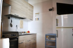 Uma cozinha com fogão, forno, armários de madeira, geladeira e um armário azul.