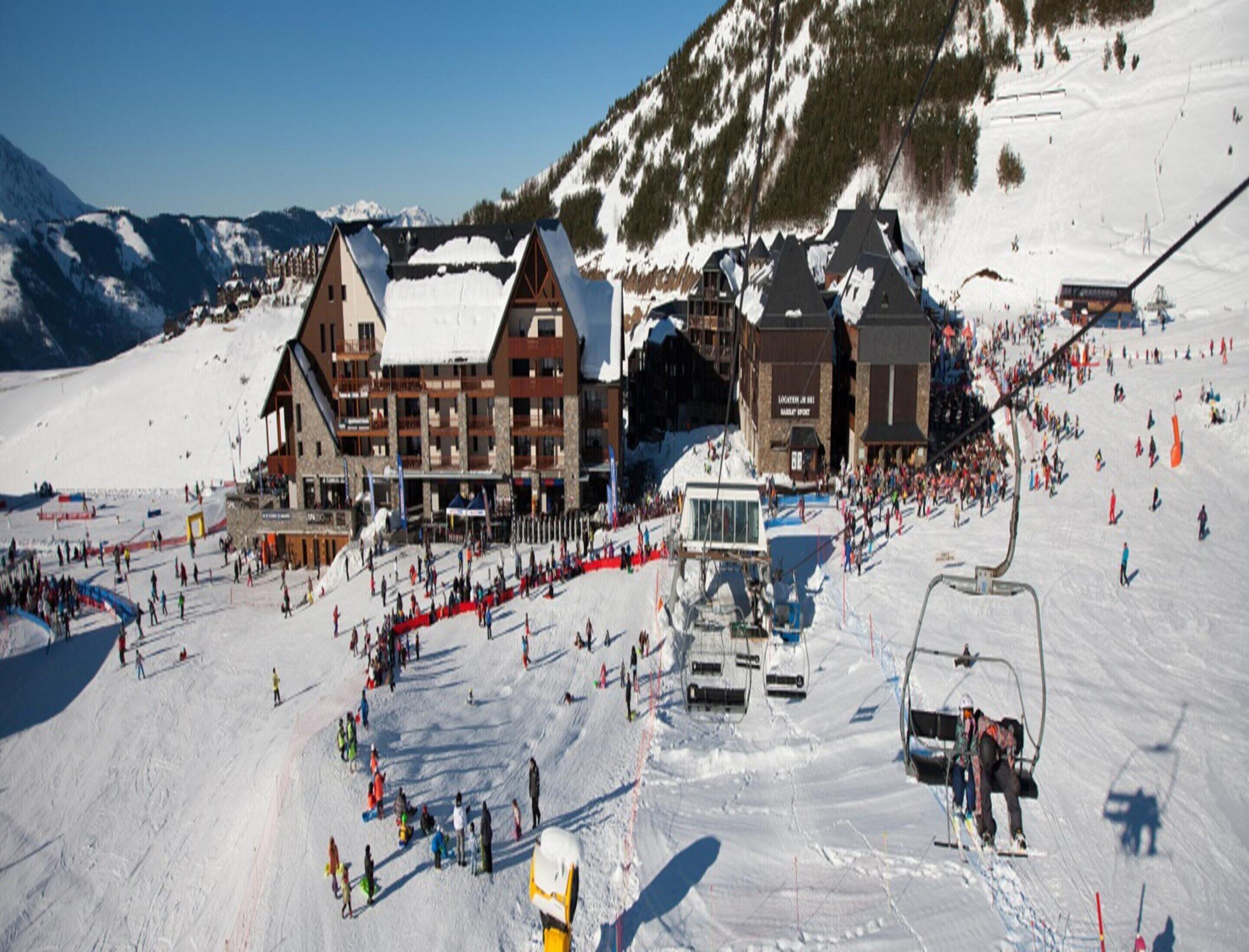 Une station de ski dotée d’un grand bâtiment, de remontées mécaniques et offrant un paysage enneigé.