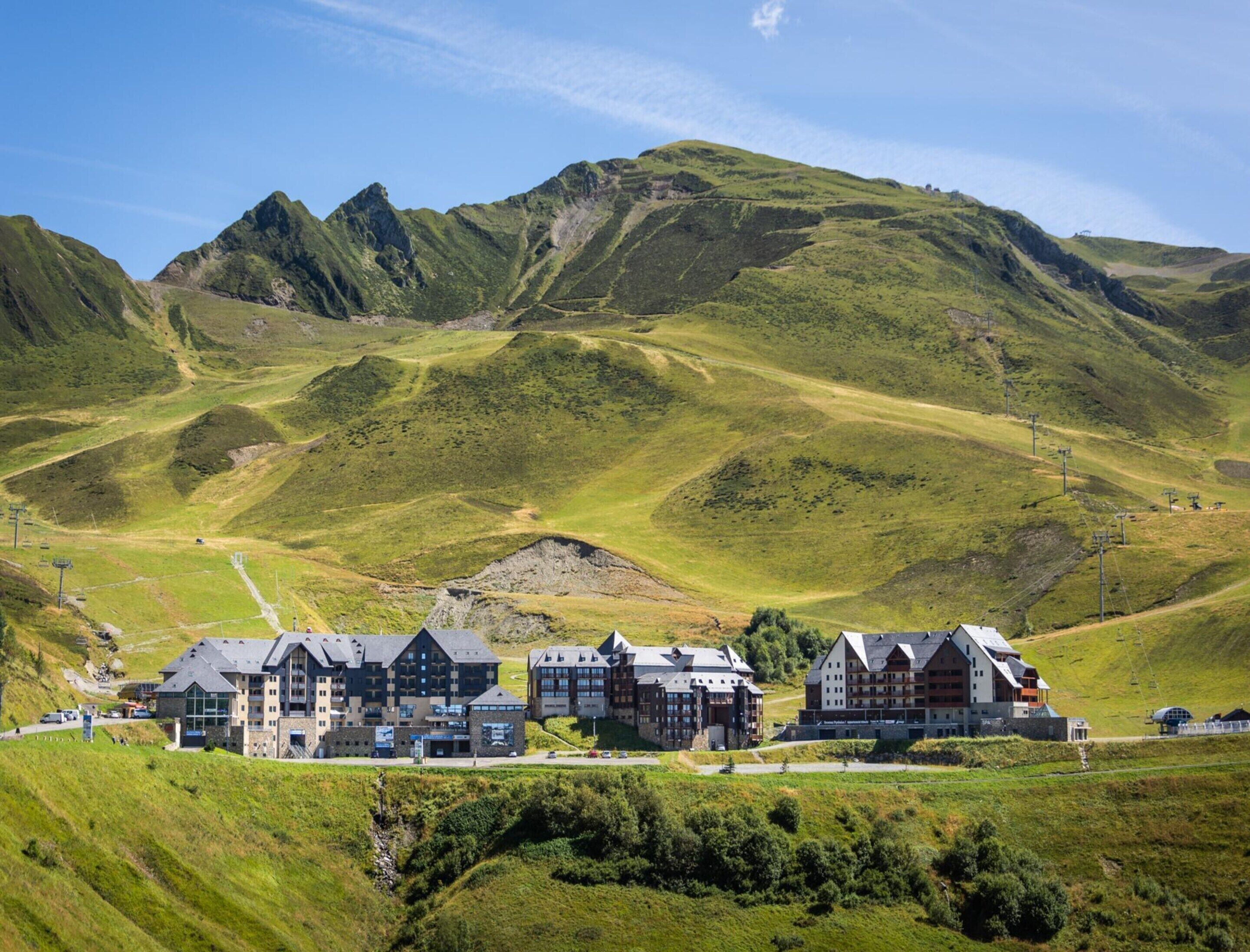 A hotel with multiple buildings, set against a mountainous backdrop.